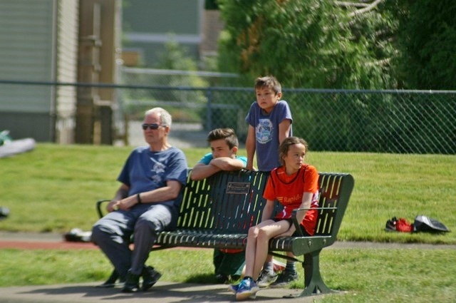Coach Rod Constable sitting on a bench with young Club Rapide athletes
